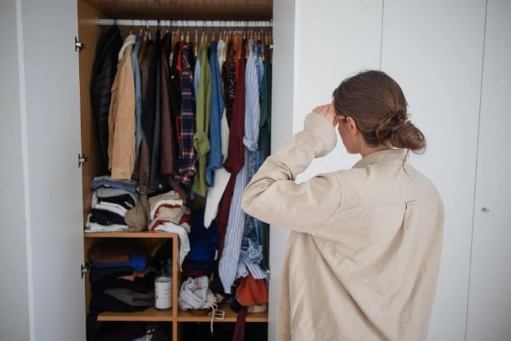 Woman reviewing clothes in an open wardrobe before a decluttering consultation