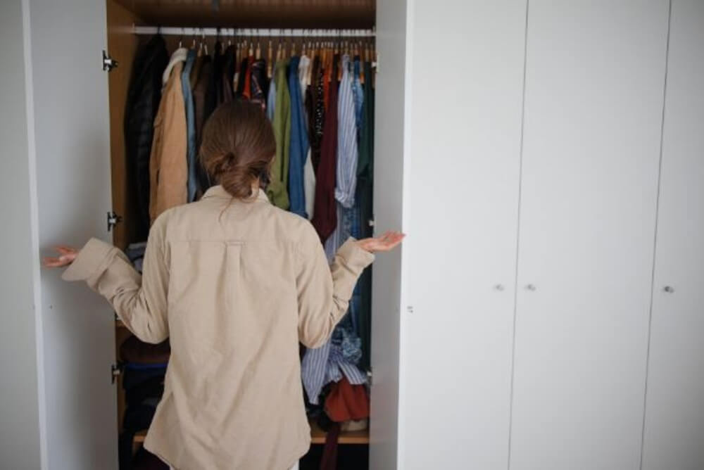 oman standing in front of an open wardrobe during an online decluttering consultation