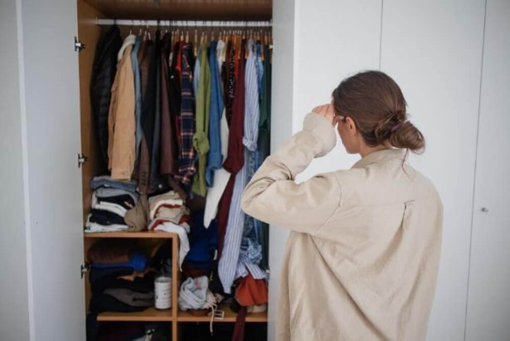 Woman reviewing clothes in her wardrobe during the LET IT GO online decluttering program